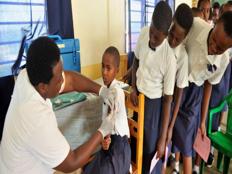 UNICEF/Laurent Rusanganwa. Una joven de Rwanda recibe su vacuna contra el Virus del Papiloma Humano mientras sus compañeros de clase miran atentamente