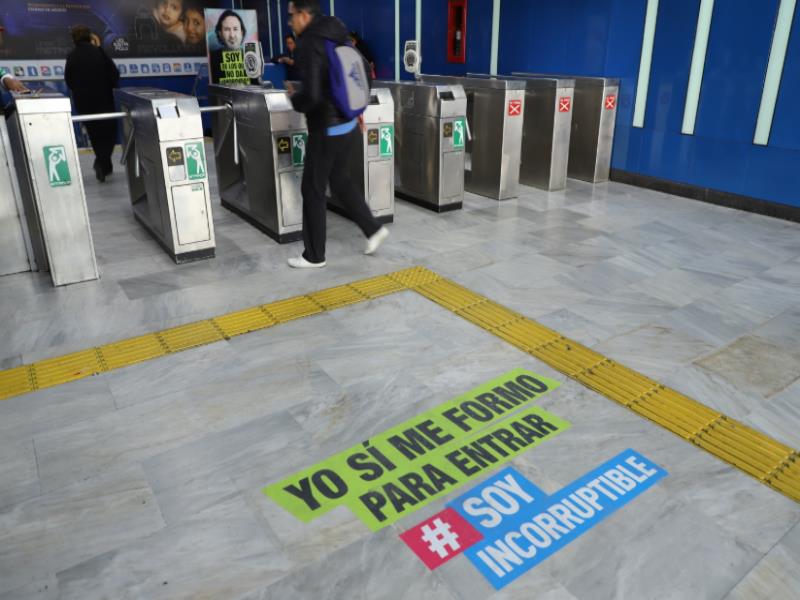 Usuario del Metro accede a la estación, en el piso se lee la frase: Yo sí me formo para entrar #SoyIncorruptible