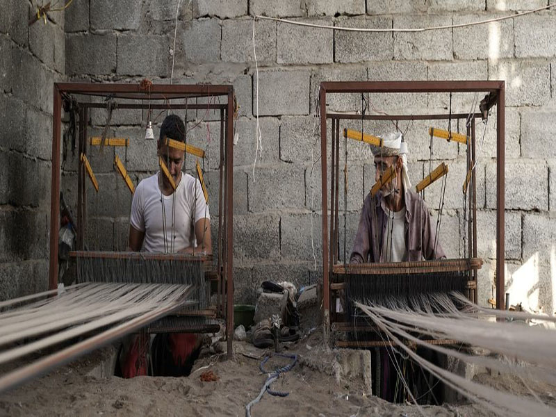 © OIT/Abdulhakeem Obadi/Gabreez Dos trabajadoras tejen a mano telas tradicionales ma'awiz en Yemen.